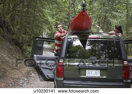 Man tying kayak on car roof in forest View Large Photo Image Stock Image - Man tying kayak on car roof in forest. Fotosearch