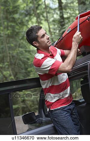 Man tying kayak on car roof in forest View Large Photo Image Stock Image - Man tying kayak on car roof in forest. Fotosearch