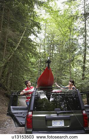 Man tying kayak on car roof in forest View Large Photo Image Stock Image - Man tying kayak on car roof in forest. Fotosearch