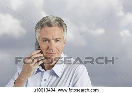Picture - Man using phone in front of clous. Fotosearch
