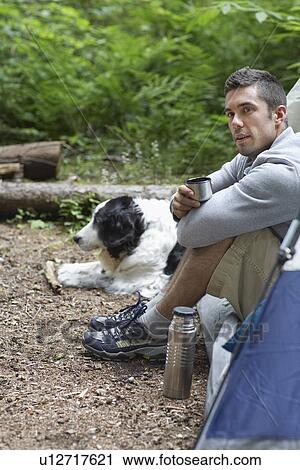 Man with dog sitting by tent View Large Photo Image Stock Image - Man with dog sitting by tent. Fotosearch