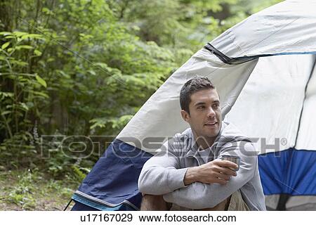 Man with drink sitting by tent View Large Photo Image Stock Photo - Man with drink sitting by tent. Fotosearch