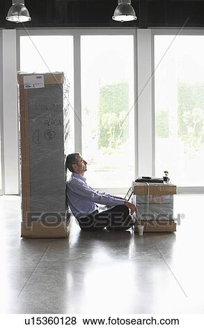 Man with laptop resting between packages in empty office View Large Photo Image Stock Photo - Man with laptop resting between packages in empty office. Fotosearch