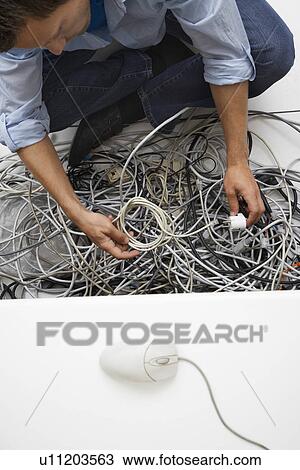 Man working on tangle of computer wires in office View Large Photo Image Stock Image - Man working on tangle of computer wires in office. Fotosearch