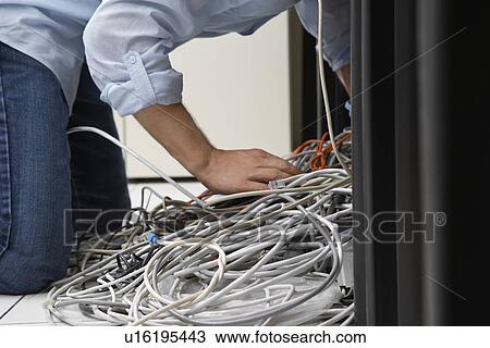 Man working on tangle of computer wires in office View Large Photo Image Stock Image - Man working on tangle of computer wires in office. Fotosearch