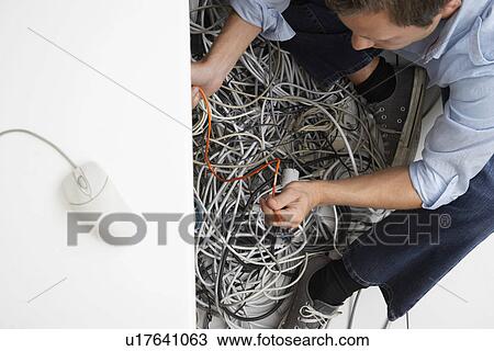 Man working on tangle of computer wires in office View Large Photo Image Stock Image - Man working on tangle of computer wires in office. Fotosearch