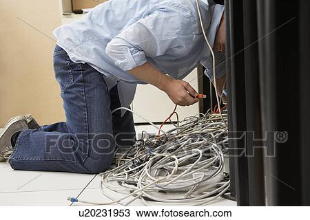 Man working on tangle of computer wires in office View Large Photo Image Stock Image - Man working on tangle of computer wires in office. Fotosearch