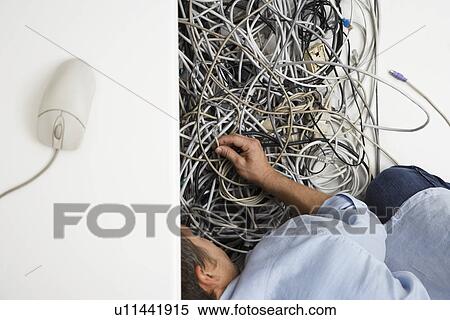 Man working on tangle of computer wires in office View Large Photo Image Stock Photography - Man working on tangle of computer wires in office. Fotosearch