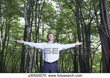 Mid adult man standing in forest with outstretched arms and closed eyes View Large Photo Image Stock Image - Mid adult man standing in forest with outstretched arms and closed eyes. Fotosearch