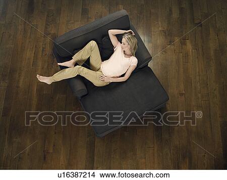 Picture - Mid adult woman sleeping on sofa view from above. Fotosearch