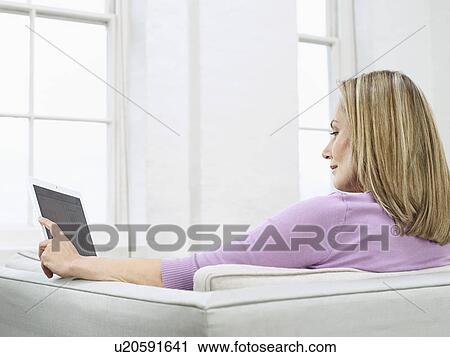 Mid adult woman using laptop on sofa profile View Large Photo Image Stock Image - Mid adult woman using laptop on sofa profile. Fotosearch