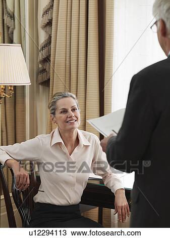 Middle-aged business man standing in front of business woman sitting down at desk View Large Photo Image Stock Image - Middle-aged business man standing in front of business woman sitting down at desk. Fotosearch
