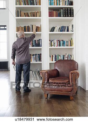 Middle-aged man taking book from shelf back view View Large Photo Image Stock Image - Middle-aged man taking book from shelf back view. Fotosearch