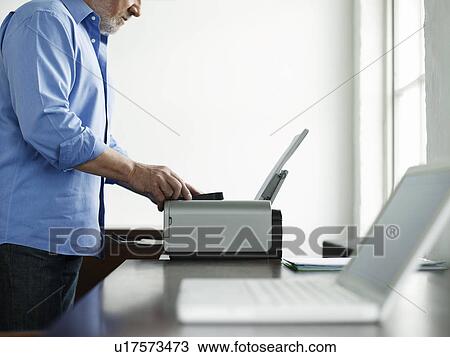 Stock Image - Middle-aged man using printer side view mid section. Fotosearch