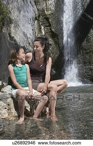 Mother and daughter (10-12) sitting on rock by river View Large Photo Image Stock Photograph - Mother and daughter (10-12) sitting on rock by river. Fotosearch