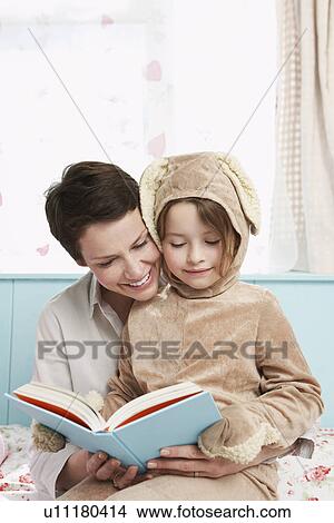 Mother and daughter (5-6) in bedroom reading book girl in bunny costume View Large Photo Image Picture - Mother and daughter (5-6) in bedroom reading book girl in bunny costume. Fotosearch