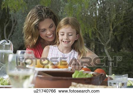 Mother and daughter (5-6) sitting at garden table smiling View Large Photo Image Stock Photograph - Mother and daughter (5-6) sitting at garden table smiling. Fotosearch