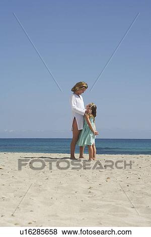 Mother and daughter (5-6) standing face to face on beach View Large Photo Image Stock Photo - Mother and daughter (5-6) standing face to face on beach. Fotosearch