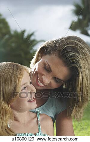 Stock Photo - Mother and daughter (5-6) talking and laughing outdoors. Fotosearch