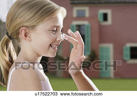 Stock Image - Mother applying sunscreen to daughter's (5-6) nose side view close-up of hand. Fotosearch