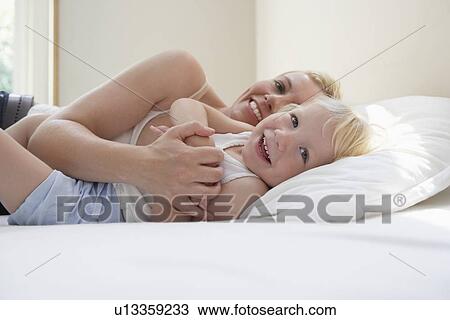 Mother embracing daughter (3-4) in bed smiling View Large Photo Image Stock Image - Mother embracing daughter (3-4) in bed smiling. Fotosearch