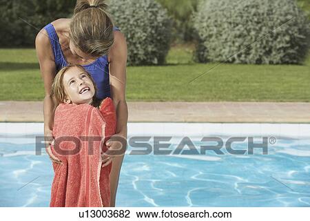 Mother embracing daughter (5-6) wrapped in towel by pool View Large Photo Image Stock Image - Mother embracing daughter (5-6) wrapped in towel by pool. Fotosearch