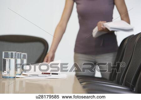 Stock Photography - Office worker arranging documents on conference table mid section. Fotosearch