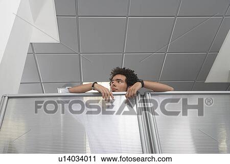 Stock Image - Office worker peering over cubicle wall. Fotosearch
