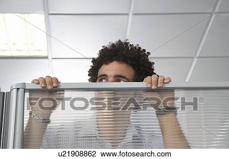 Stock Image - Office worker peering over cubicle wall. Fotosearch