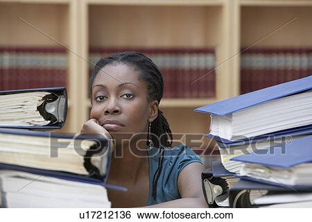 Office worker sitting behind stacks of documents in office portrait View Large Photo Image Stock Photograph - Office worker sitting behind stacks of documents in office portrait. Fotosearch