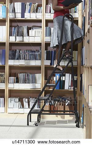 Office worker standing on ladder in file storage room low section View Large Photo Image Stock Image - Office worker standing on ladder in file storage room low section. Fotosearch
