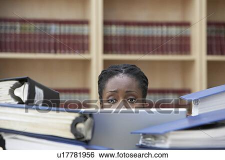 Office worker using laptop sitting behind stacks of documents in office high section View Large Photo Image Stock Photograph - Office worker using laptop sitting behind stacks of documents in office high section. Fotosearch