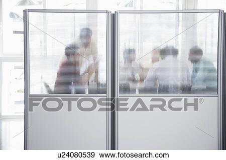Stock Photo - Office workers meeting behind cubicle wall in office. Fotosearch