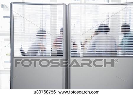 Office workers meeting behind cubicle wall in office View Large Photo Image Stock Photograph - Office workers meeting behind cubicle wall in office. Fotosearch