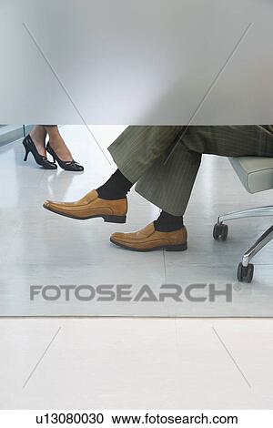 Stock Image - Office workers sitting in office low section (feet). Fotosearch