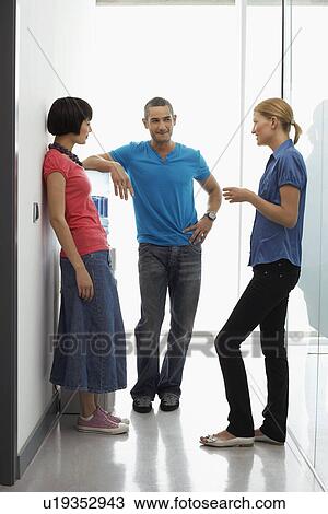 Office workers talking by water cooler in hallway View Large Photo Image Stock Image - Office workers talking by water cooler in hallway. Fotosearch