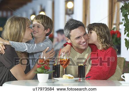 Parents and children (7-9) with drinks embracing at restaurant View Large Photo Image Picture - Parents and children (7-9) with drinks embracing at restaurant. Fotosearch