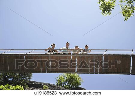 Parents and two sons (7-12) on bridge looking down View Large Photo Image Stock Image - Parents and two sons (7-12) on bridge looking down. Fotosearch