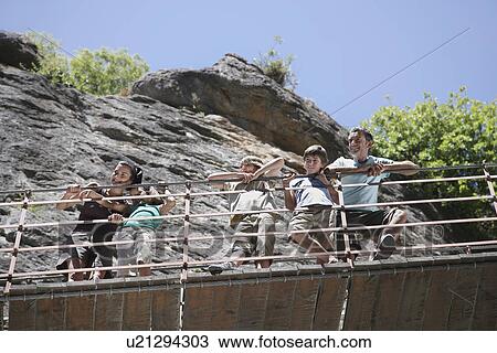 Parents and two sons (7-12) on bridge looking down View Large Photo Image Stock Image - Parents and two sons (7-12) on bridge looking down. Fotosearch