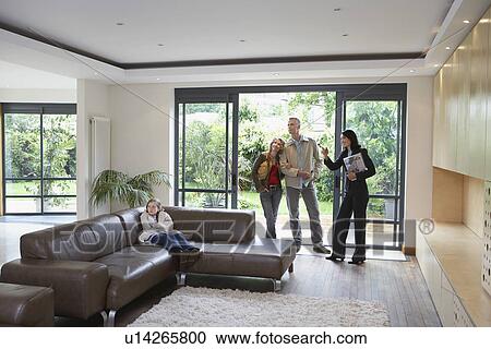 Stock Image - Parents with bored daughter (7-9) and estate agent observing new property. Fotosearch