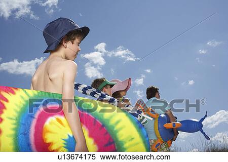 Parents with sons (6-12) carrying beach accessories back view View Large Photo Image Stock Photography - Parents with sons (6-12) carrying beach accessories back view. Fotosearch