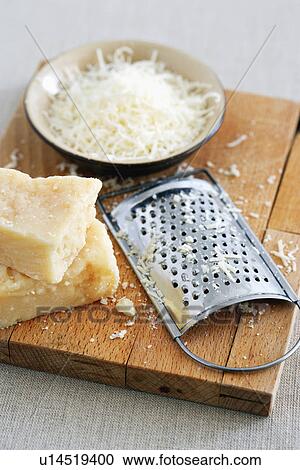 Parmesan cheese and grater on cutting board at table View Large Photo Image Stock Image - Parmesan cheese and grater on cutting board at table. Fotosearch