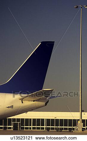 Stock Image - Passenger jet tailplane against airport terminal. Fotosearch