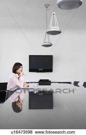 Stock Photo - Pensive business woman sitting at table in conference room. Fotosearch