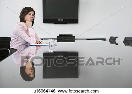 Stock Photograph - Pensive business woman sitting at table in conference room. Fotosearch