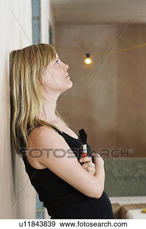Pensive woman holding paint brush leaning against wall side view View Large Photo Image Stock Photo - Pensive woman holding paint brush leaning against wall side view. Fotosearch