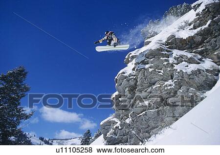 Stock Photo - Person on snowboard jumping low angle view. Fotosearch