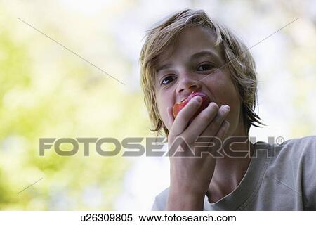 Stock Photography - Portrait of boy (10-12) eating apple. Fotosearch