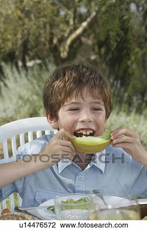 Portrait of boy (5-6) eating melon at garden table View Large Photo Image Stock Image - Portrait of boy (5-6) eating melon at garden table. Fotosearch