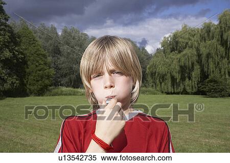 Portrait of boy (7-9) blowing whistle in meadow View Large Photo Image Stock Photography - Portrait of boy (7-9) blowing whistle in meadow. Fotosearch